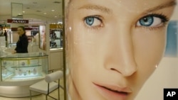 A Bangkok cosmetics sales clerk looks on near a large ad for skin whitening cream. With rising incomes, more and more Asians are turning to products to lighten their skin color, and cosmetics giants are cashing in. (AP Photo/Sakchai Lalit)