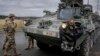FILE - Soldiers of the 2nd Cavalry Regiment stand next to a Stryker combat vehicle in Vilseck, Germany, Feb. 9, 2022.