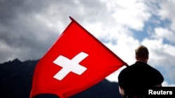 FILE - A man dressed in traditional costume holds a Swiss flag at the 28th Federal Yodeling Festival in Interlaken, Switzerland, June 19, 2011.
