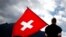 FILE - A man dressed in traditional costume holds a Swiss flag at the 28th Federal Yodeling Festival in Interlaken, Switzerland, June 19, 2011.