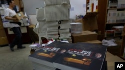 FILE - A worker walks past a stack of books by former Beijing mayor Chen Xitong, titled "Conversation with Chen Xitong," at a publisher's warehouse, one day before the launch of the book in Hong Kong.