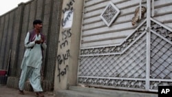 FILE - A man looks at graffiti supporting the Islamic State group as he walks past an entrance of a compound in Karachi, Pakistan, Nov. 12, 2014. Authorities in Pakistan are reported to have arrested five suspected IS operatives in Karachi Monday.