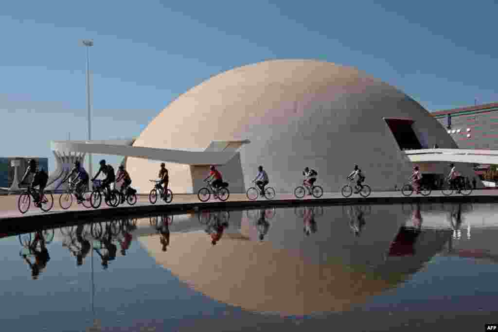 People cycle past the National Museum of the Republic, marking World Car Free Day, in Brasilia, Brazil, Thursday Sept. 22, 2011. World Car Free Day is marked annually whereby participants switch from using cars and walk, bike, use mass transit, work from 