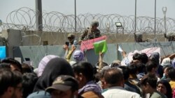 FILE - U.S. soldier holds a "Gate Closed" sign as hundreds of people gather near an evacuation checkpoint on the perimeter of Hamid Karzai International Airport, in Kabul, Afghanistan, Aug. 26, 2021.