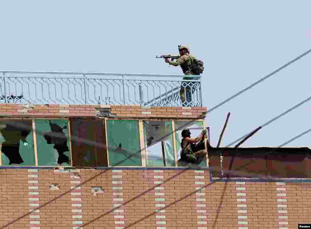 Afghan security forces take position on a building where the attackers were hiding on a jail compound in Jalalabad.