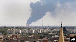 Black smoke billows over the skyline as a fire at the oil depot for the airport rages out of control after being struck in the crossfire of warring militias battling for control of the airfield, in Tripoli, Libya, July 28, 2014. 