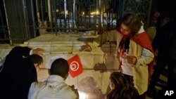 Warga Tunisia menyalakan lilin di pintu masuk Museum Nasional Bardo di Tunis, pasca serangan pria bersenjata 18 Maret 2015 (AP Photo/Michel Euler).