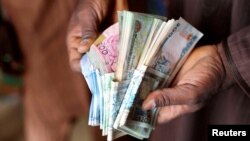 FILE — A man counts Nigerian naira notes in a market place in Yola, Nigeria, February 22, 2023. 