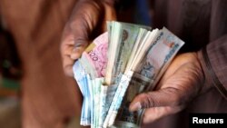 FILE —A man counts Nigerian naira notes at a market place in Yola, Nigeria, Feb. 22, 2023.