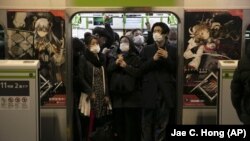 In this March 2, 2020, file photo, commuters wearing masks stand in a packed train at the Shinagawa Station in Tokyo. (AP Photo/Jae C. Hong, File)