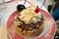 FILE - A waffle with bananas, chocolate, butter, syrup and whipped cream with a cherry on top is at Serendipity 3 restaurant in New York City on Sunday, October 8, 2023. (AP Photo/Ted Shaffrey)