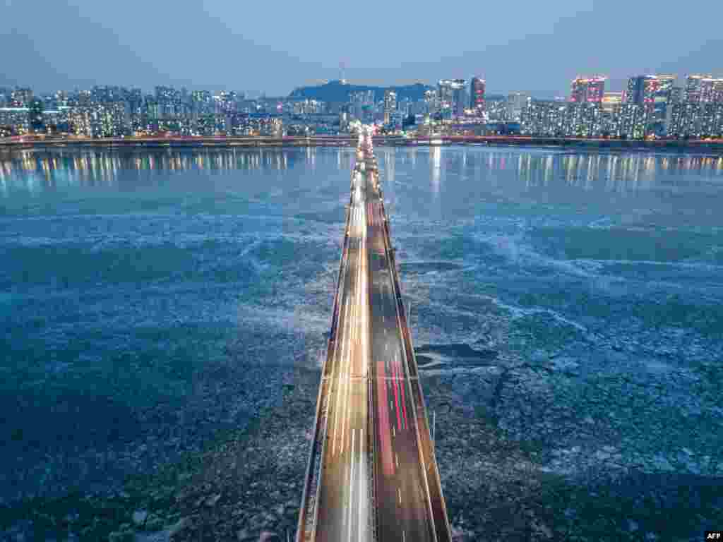 A general view of traffic passing over a bridge above the frozen Han river, before the Seoul city skyline, South Korea.