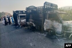 Petugas keamanan berdiri di dekat kendaraan yang hangus di lokasi penembakan di jalan raya nasional di distrik Musakhail, Provinsi Balochistan pada 26 Agustus 2024. (Foto: AFP)