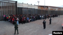 FILE - U.S. Border Patrol agents keep watch on a large group of migrants who they say were attempting to cross the U.S.-Mexico border illegally, in El Paso, Texas, May 29, 2019.