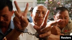 Mam Sonando (C), owner of a local independent radio station and land rights campaigner, gestures as he arrives at the Appeal Court in Phnom Penh, March 5, 2013. 