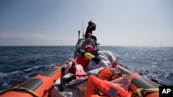 FILE - Proactiva Open Arms crew conduct a search-and-rescue operation in the Mediterranean Sea, 12 nautic miles from the Libyan coast, April 13, 2017.