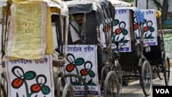 Seorang pengendara becak di Calcutta duduk di dalam becaknya yang dihiasi atribut partai Kongres Trinamool, Senin (18/4).