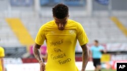 FILE - Jadon Sancho of the German club Borussia Dortmund celebrates scoring a goal with a “Justice for George Floyd” shirt during a match in Paderborn, Germany, May 31, 2020.