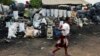 Children walk past charcoal sellers in Kitwe, Zambia, Jan. 17, 2015. 