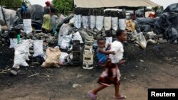 Children walk past charcoal sellers in Kitwe, Zambia, Jan. 17, 2015. 