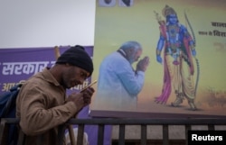 A Hindu devotee reads a religious book in front of a hoarding of Lord Ram and Indian Prime Minister Narendra Modi on a street ahead of the opening of the grand temple of Lord Ram in Ayodhya in India, January 19, 2024.