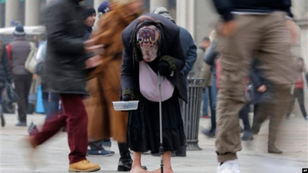 Seorang perempuan mengemis di antara orang lewat di jalanan kota Milan (Januari 2013). Ekonomi zona Euro masih lemah dan pengangguran terus meningkat. 
