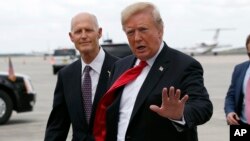 El presidente Donald Trump, acompañado por el gobernador de Florida Rick Scott, saluda a partidarios después de aterrizar en Orlando, el lunes 8 de octubre de 2018, (Foto AP / Alex Brandon)