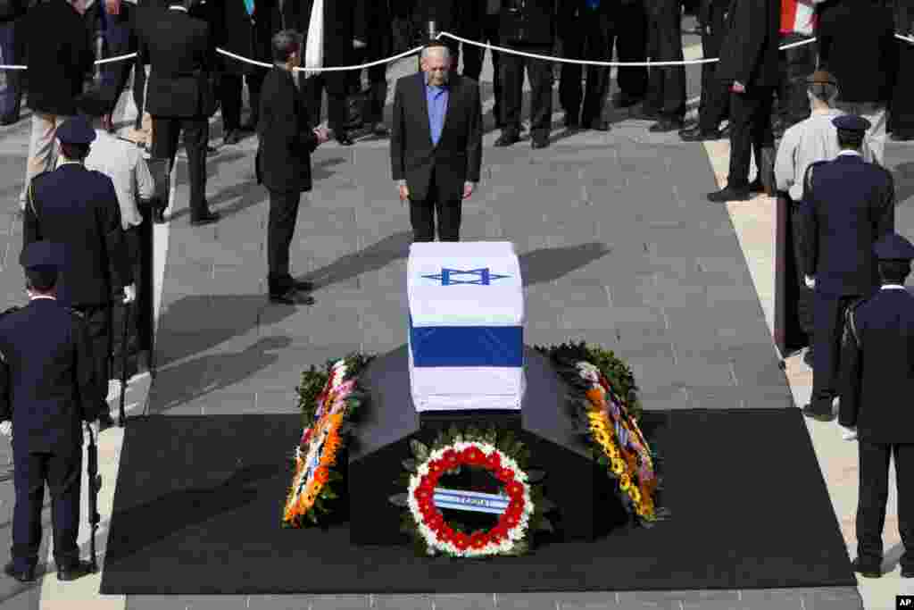 Mantan perdana menteri Israel Ehud Olmert memberi penghormatan terakhir di depan peti jenazah Ariel Sharon di Plaza Knesset, Yerusalem (12/1). (AP/Oded Balilty)