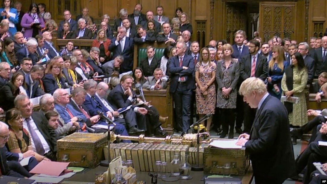 Britain's Prime Minister Boris Johnson delivers a statement to lawmakers inside a crowded House of Commons in London, Oct. 19, 2019. At a rare weekend session, Johnson implored legislators to ratify a last-minute Brexit deal he struck with EU leaders.