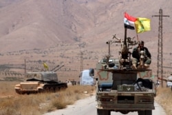 FILE - Hezbollah and Syrian flags flutter on a military vehicle in Western Qalamoun, Syria, Aug. 28, 2017.