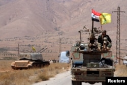 FILE - Hezbollah and Syrian flags flutter on a military vehicle in Western Qalamoun, Syria, Aug.&nbsp;28, 2017.