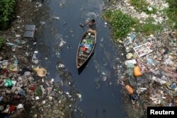 FILE - A man on a boat collects plastic materials from dirty water in Dhaka, Bangladesh, April 17, 2019.