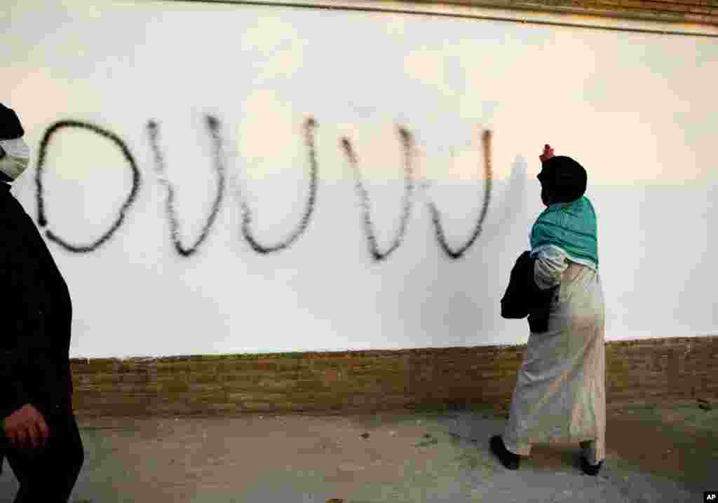 A cleric spray paints graffiti inside the British embassy compound. (REUTERS/Stringer)