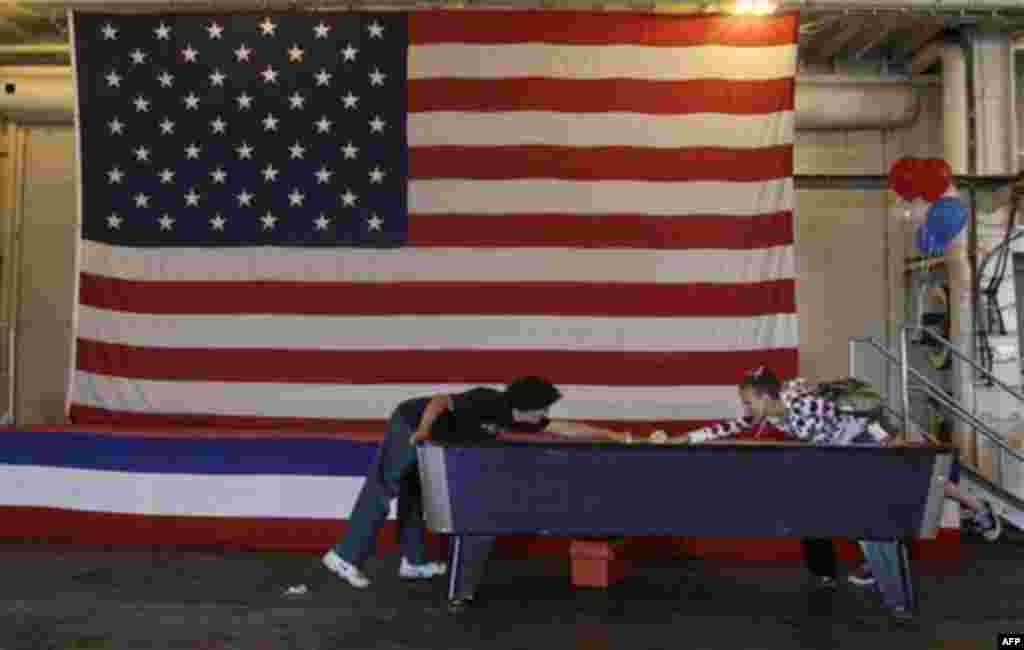 Andre Moyce, left, and Skadi McKeown play air hockey on the hangar deck of the USS Hornet during Fourth of July festivities in Alameda, Calif., Monday, July 4, 2011. (AP Photo/Jeff Chiu)