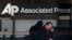 A man looks down at his smartphone as he walks past the offices of the Associated Press in Manhattan, New York, May 13, 2013.