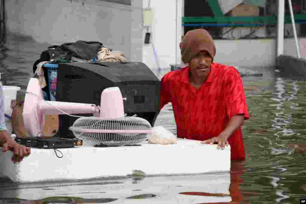 A man floats valuables out of his flooded Ayutthaya neighborhood, October 6, 2011. (VOA - D. Schearf)