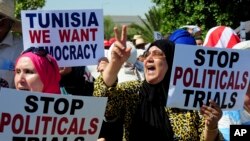 FILE - Supporter of the leader of the Ennahdha party Rached Ghannouchi, hold placards as they stage a protest at Tunisia's anti-terrorism unit in Tunis, Tunisia, Tuesday, July 19, 2022. 