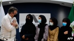The Mexican Secretary of Foreign Affairs Marcelo Ebrard (L) welcomes four Afghan women, members of the Afghanistan Robotic team, during their arrival to Mexico after asking for refuge, at the Airport in Mexico City, on August 24, 2021.