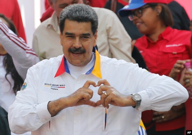 FILE - Venezuela's President Nicolas Maduro flashes a hand-heart symbol to supporters outside Miraflores presidential palace in Caracas, Venezuela, May 20, 2109.
