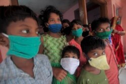 Evacuated children wearing masks as a precaution against the spread of coronavirus stand at a relief camp at Paradeep, on the Bay of Bengal coast in Orissa, India, Tuesday, May 19, 2020.