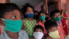 Evacuated children wearing masks as a precaution against the spread of coronavirus stand at a relief camp at Paradeep, on the Bay of Bengal coast in Orissa, India, Tuesday, May 19, 2020.