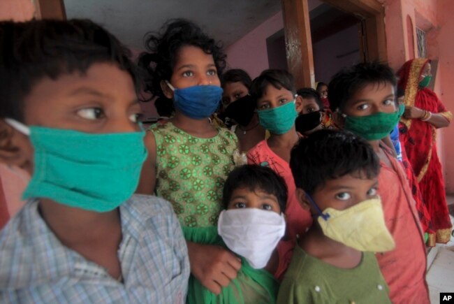 Evacuated children wearing masks as a precaution against the spread of coronavirus stand at a relief camp at Paradeep, on the Bay of Bengal coast in Orissa, India, Tuesday, May 19, 2020.