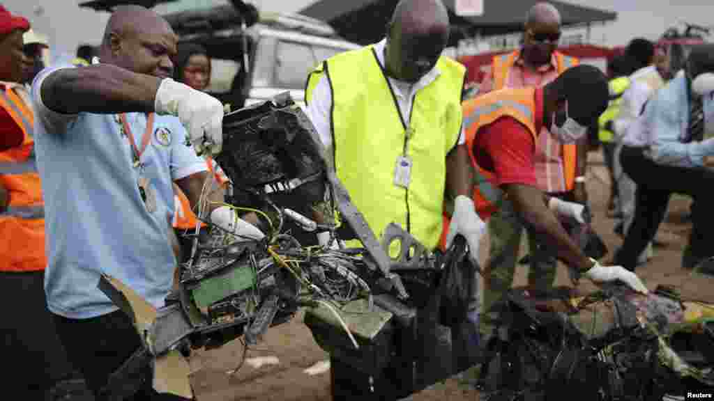 Air safety officials collect parts of a plane after it crashed near the Lagos airport.