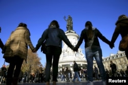 FILE - People hold hands to form a human solidarity chain near the site of the attack at the Bataclan concert hall in Paris, Nov. 15, 2015.