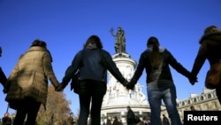 FILE - People hold hands to form a human solidarity chain near the site of the attack at the Bataclan concert hall in Paris, Nov. 15, 2015. 