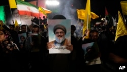 Seorang ulama memegang poster pemimpin Hizbullah yang terbunuh Hassan Nasrallah pada demonstrasi anti-Israel di Lapangan Felestin (Palestina) di Teheran, Iran, Selasa, 1 Oktober 2024. (Foto: AP)