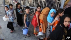 FILE - Iraqi children, most of them internally displaced persons, wait in line for free food being distributed at a mosque in Baghdad, Iraq, June 23, 2015.