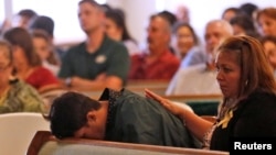 FILE - A graduating senior from Santa Fe High School reacts to Friday's school shooting during prayer services at the Arcadia First Baptist Church in Santa Fe, Texas, May 20, 2018.