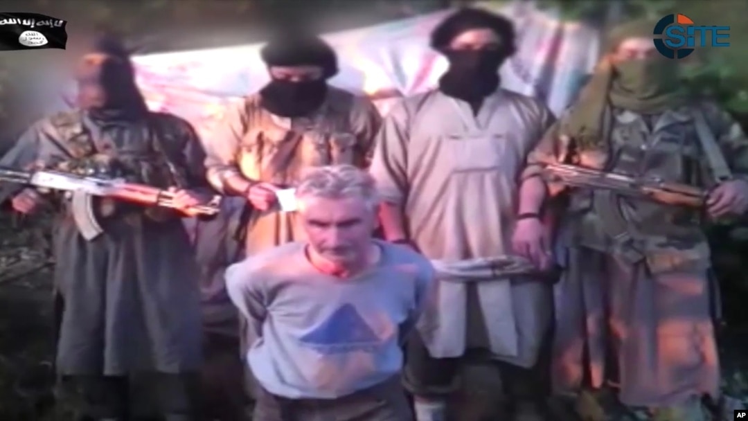 In this still image from video published on the Internet on Sept. 24, 2014, by a group calling itself Jund al-Khilafah, or Soldiers of the Caliphate, members of the group stand behind French mountaineer Herve Gourdel just before beheading him.