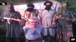 In this still image from video published on the Internet on Sept. 24, 2014, by a group calling itself Jund al-Khilafah, or Soldiers of the Caliphate, members of the group stand behind French mountaineer Herve Gourdel just before beheading him.